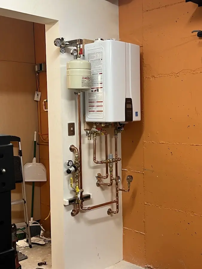 Plumbing technician inspecting water heater connections in Cleves
